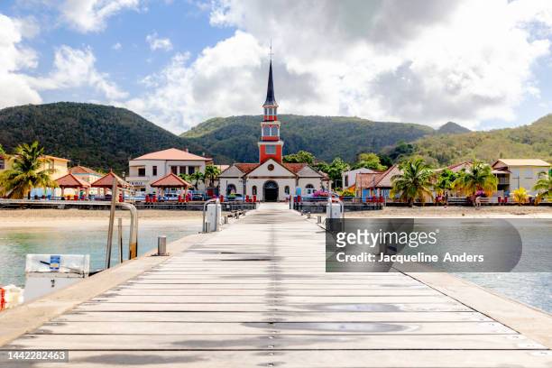 saint henri church on the beach of les anses d'arlet, martinique with a wooden walkway - isla martinica fotografías e imágenes de stock