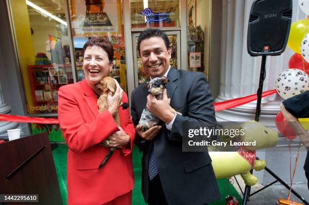 Head Carol Schatz and City Council Member José Huizar laughing pose for a portrait holding puppies during the ribbon-cutting and grand opening of...