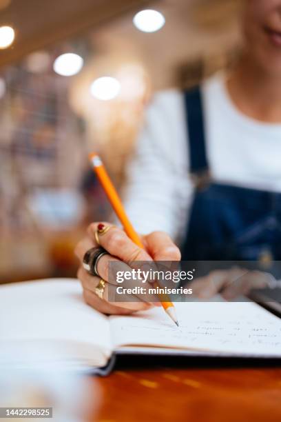 close up photo of woman hands writing notes in the cafe - poeta imagens e fotografias de stock
