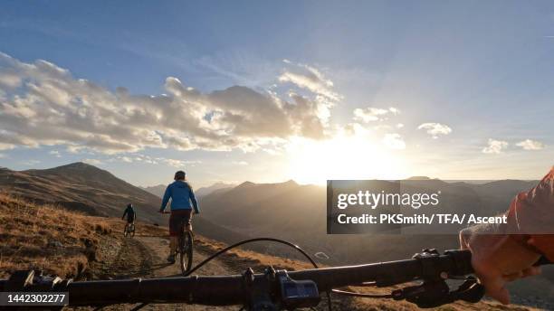 mountain bikers ride into setting sun on trail - following path stock pictures, royalty-free photos & images