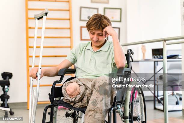 joven soldado militar sentado en silla de ruedas en un centro de rehabilitación - personal injury fotografías e imágenes de stock