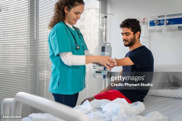 doctor wrapping bandage on  arm amputation - injured man in hospital bed stockfoto's en -beelden