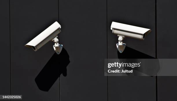 two surveillance cameras on the wall of a public building - surveillance camera stock pictures, royalty-free photos & images