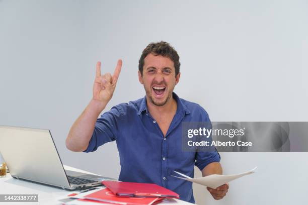 funny businessman smiling and making the heavy metal sign with his hand in the office - heavy metal horns stock pictures, royalty-free photos & images