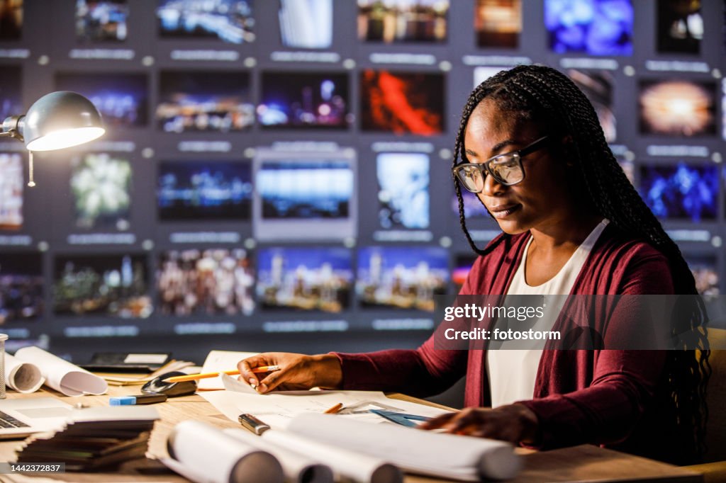Young female architect working on blueprints at her desk in a modern office