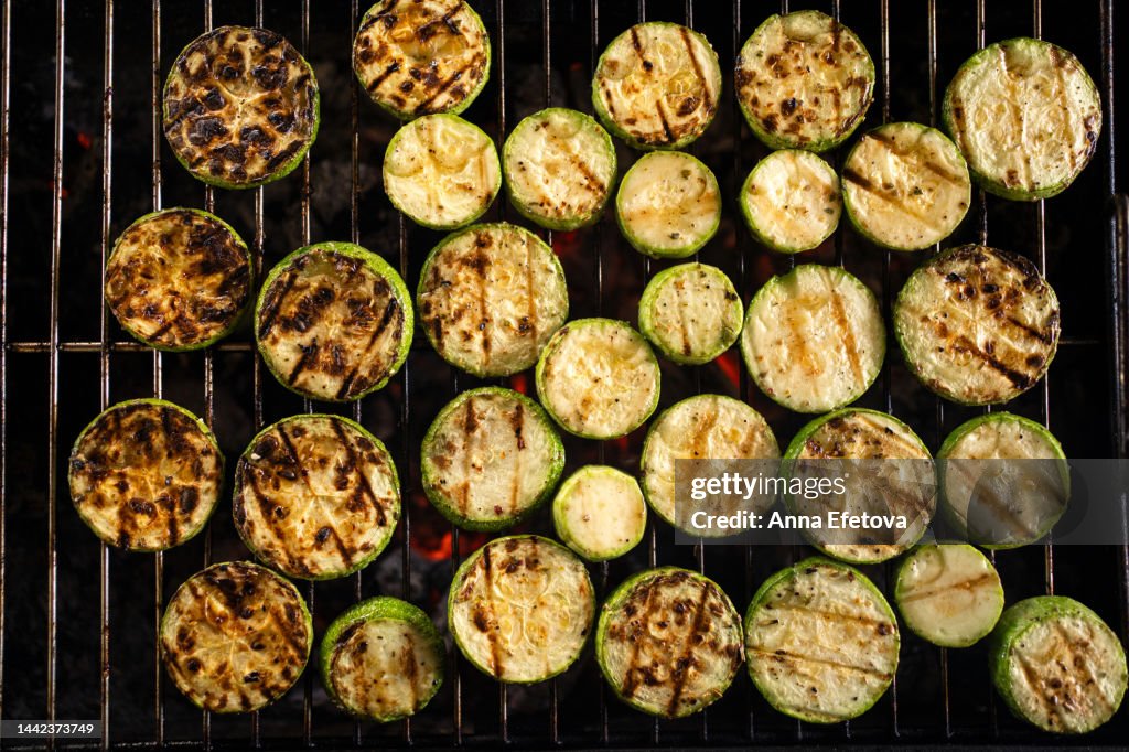Round pieces of vegetable marrow are cooking on the grill. Concept of country picnic. Photography from above