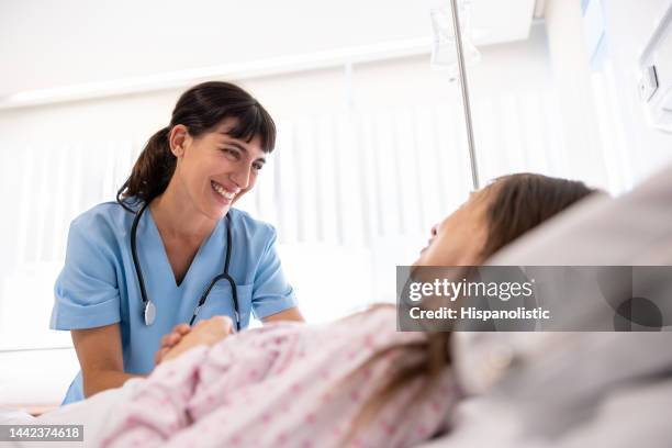 happy nurse comforting a sick patient at the hospital - postoperatief stockfoto's en -beelden