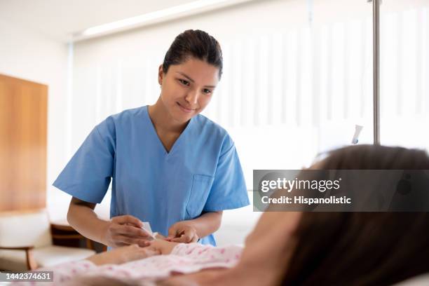 nurse putting an iv line on a hospitalized patient - katheter stockfoto's en -beelden