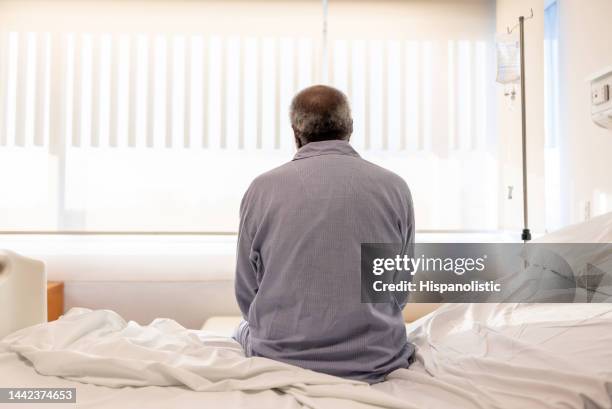 sick man sitting on the bed at the hospital - hospital bed with iv stock pictures, royalty-free photos & images