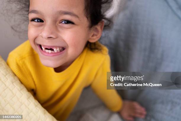 happy young mixed-race girl smiling & showing her two front missing teeth - tooth fairy stock pictures, royalty-free photos & images