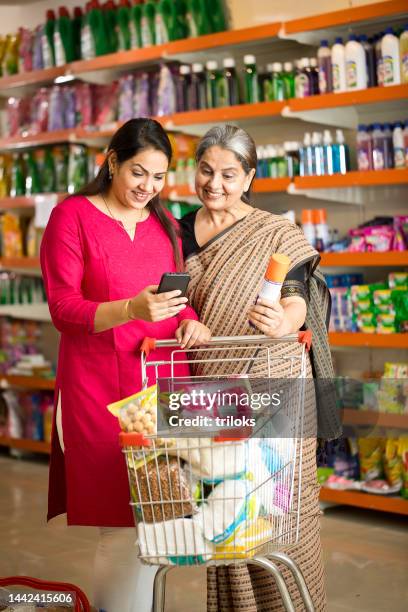 shocked mother and daughter using phone at store - daily life in india stock pictures, royalty-free photos & images