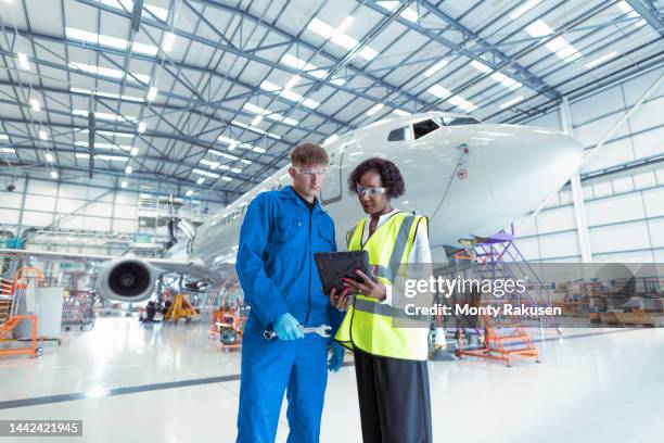 apprentice aircraft maintenance engineer with supervisor in maintenance hangar - flugzeugmechaniker stock-fotos und bilder