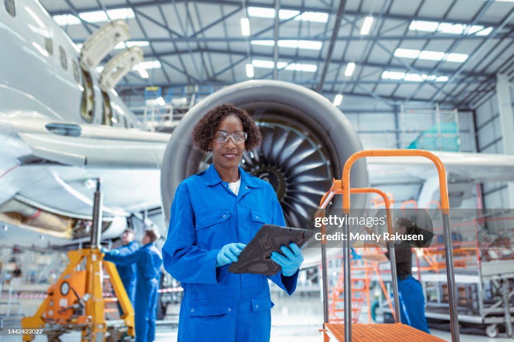 Portrait of female aircraft maintenance engineer in aircraft hangar