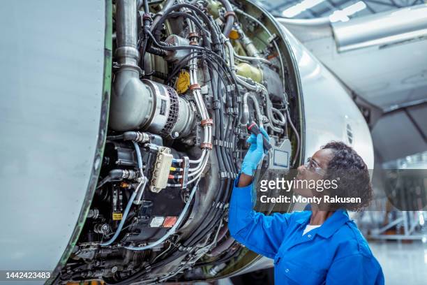 female aircraft maintenance engineer inspecting jet engine - flugzeugmechaniker stock-fotos und bilder