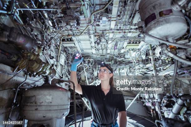 female apprentice aircraft maintenance engineer inspecting wheel well on jet - airplane wheel well stockfoto's en -beelden