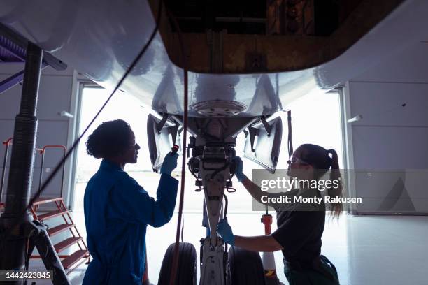 female aircraft engineers inspecting landing gear on large jet - aerospace foto e immagini stock