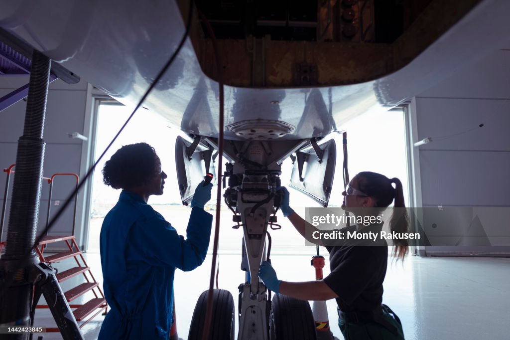 Female aircraft engineers inspecting landing gear on large jet
