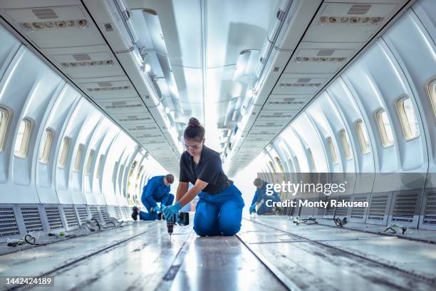 female apprentice aircraft maintenance engineer at work in empty interior of jet - kneeling stock pictures, royalty-free photos & images