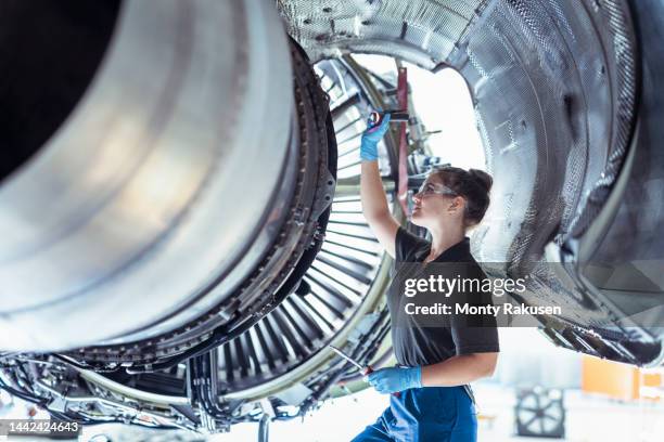 female apprentice aircraft maintenance engineer work underneath jet engine - indústria aeroespacial imagens e fotografias de stock