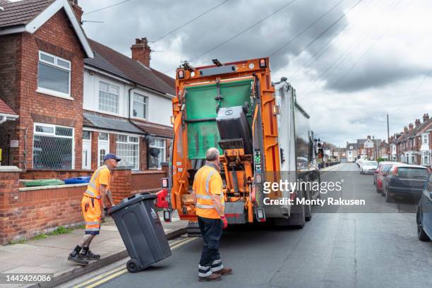 refuse collectors and refuse truck in street - garbage truck fotografías e imágenes de stock
