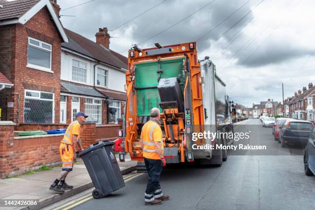 refuse collectors and refuse truck in street - garbage truck stock pictures, royalty-free photos & images