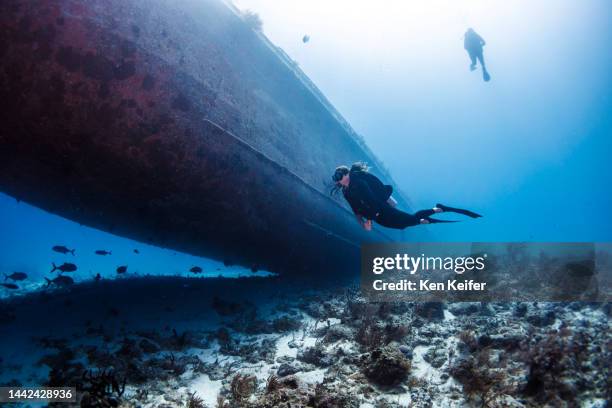 bahamas, nassau, female diver swimming near shipwreck - woman diving underwater stock pictures, royalty-free photos & images