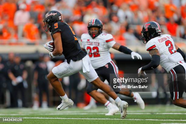 Wide receiver Bryson Green of the Oklahoma State Cowboys turns with a 19-yard catch against defensive back Reggie Pearson Jr. #2 and linebacker...
