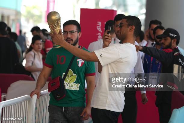 Man poses with a replica of the world cup trophy as he lines up to enter the Main Tickets Centre ahead of the FIFA World Cup Qatar 2022 on November...