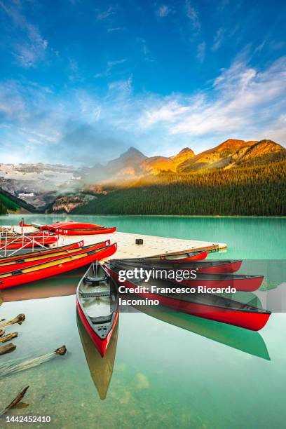 lake louise, canoe and kayak on calm water at sunrise. banff, canadian rockies, canada - lake louise stockfoto's en -beelden