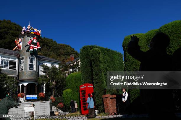 Visitors look at the giant Santa Claus wearing a bulletproof vest jacket and helmet displayed on a building at Uroko No Ie on November 18, 2022 in...