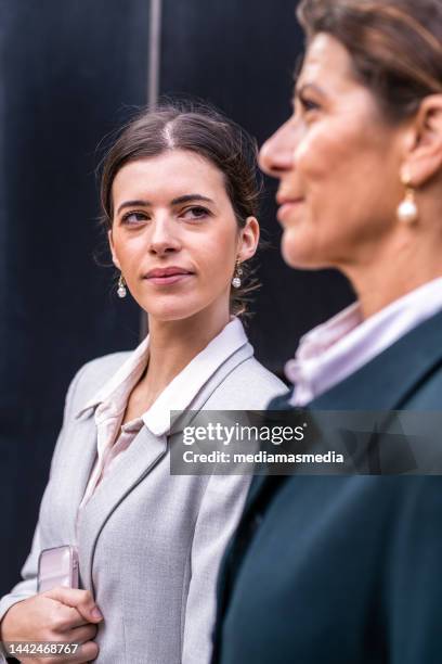 mature and wealthy senior business woman with a middle-aged daughter having a calm conversation in a premium city outdoor locations about family business - succession planning stock pictures, royalty-free photos & images