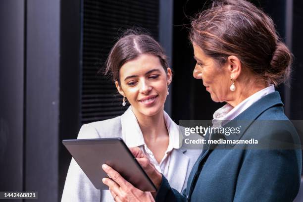 mature and wealthy senior business woman with a middle-aged daughter having a calm conversation in a premium city outdoor locations about family business - succession planning stock pictures, royalty-free photos & images