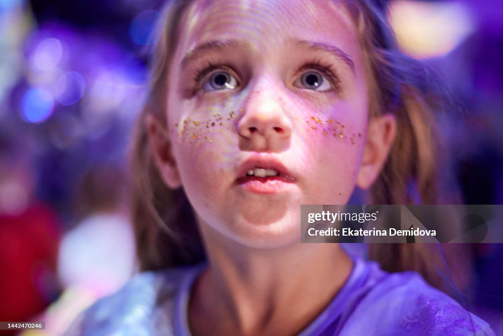 Child's face close-up on a holiday in neon light