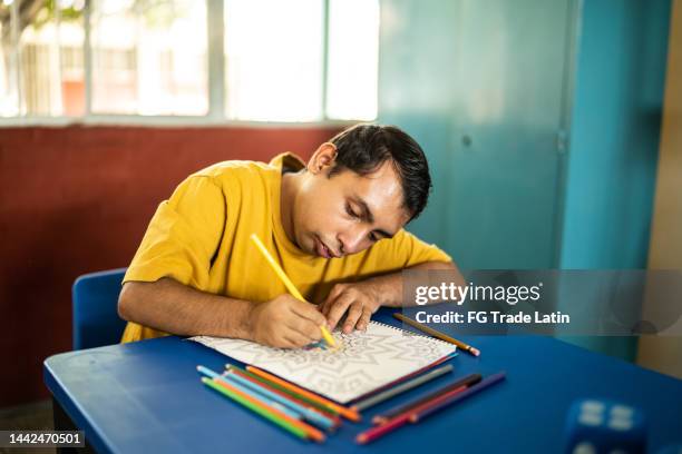 retardo psicomotor jovem desenhando na sala de aula da escola - autism - fotografias e filmes do acervo