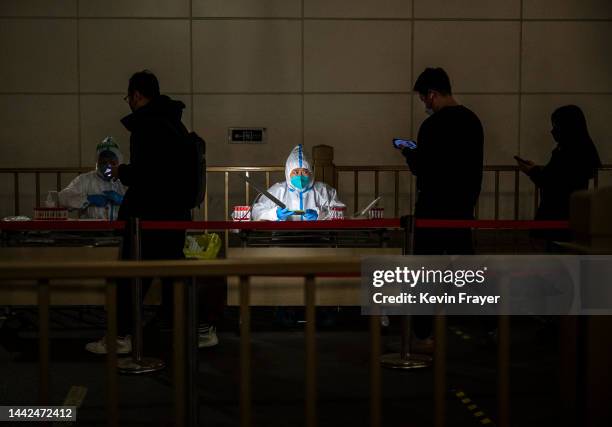 An epidemic control worker registers people for nucleic acid tests to detect COVID-19 at a public testing site on November 17, 2022 in Beijing,...