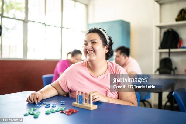 psychomotor retardation teenage girl playing didactic game in the classroom at school - autism adult stock pictures, royalty-free photos & images