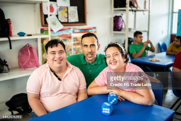 portrait of mid adult teacher with their disabled students in the classroom at school - autism adult stock pictures, royalty-free photos & images