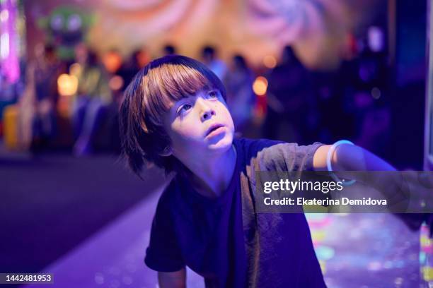 little boy presses the button on the slot machine neon night light close-up - button craft foto e immagini stock