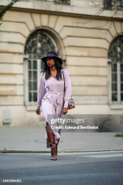 Emilie Joseph wears a black felt wool hat from Maison Michel, a pale purple wool V-neck / long sleeves / belted / slit long dress, a brown shiny...