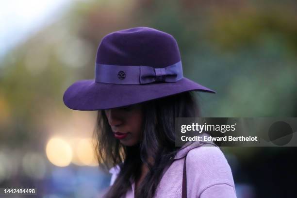 Emilie Joseph wears a black felt wool hat from Maison Michel, a pale purple wool V-neck / long sleeves / belted / slit long dress, during a street...