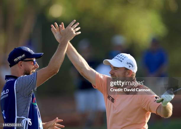 Richie Ramsay of Scotland celebrates with his caddie after holing his third shot from almost 200 yards for an eagle three on the 18th hole during the...