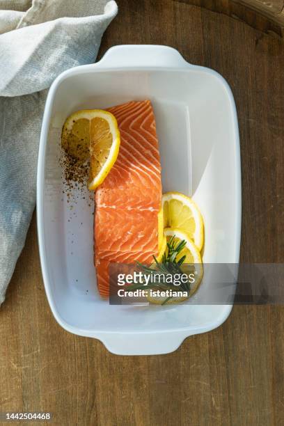 fresh salmon fillet with lemon slices and rosemary in dish, preparing food, ingredients - low carb diet stock pictures, royalty-free photos & images