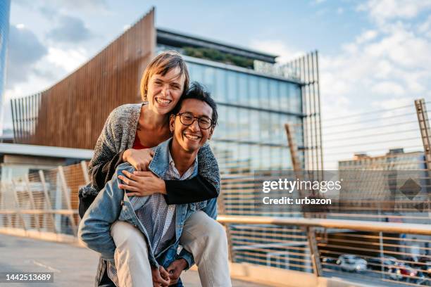 young couple piggyback riding on the street in milan - cavalitas imagens e fotografias de stock