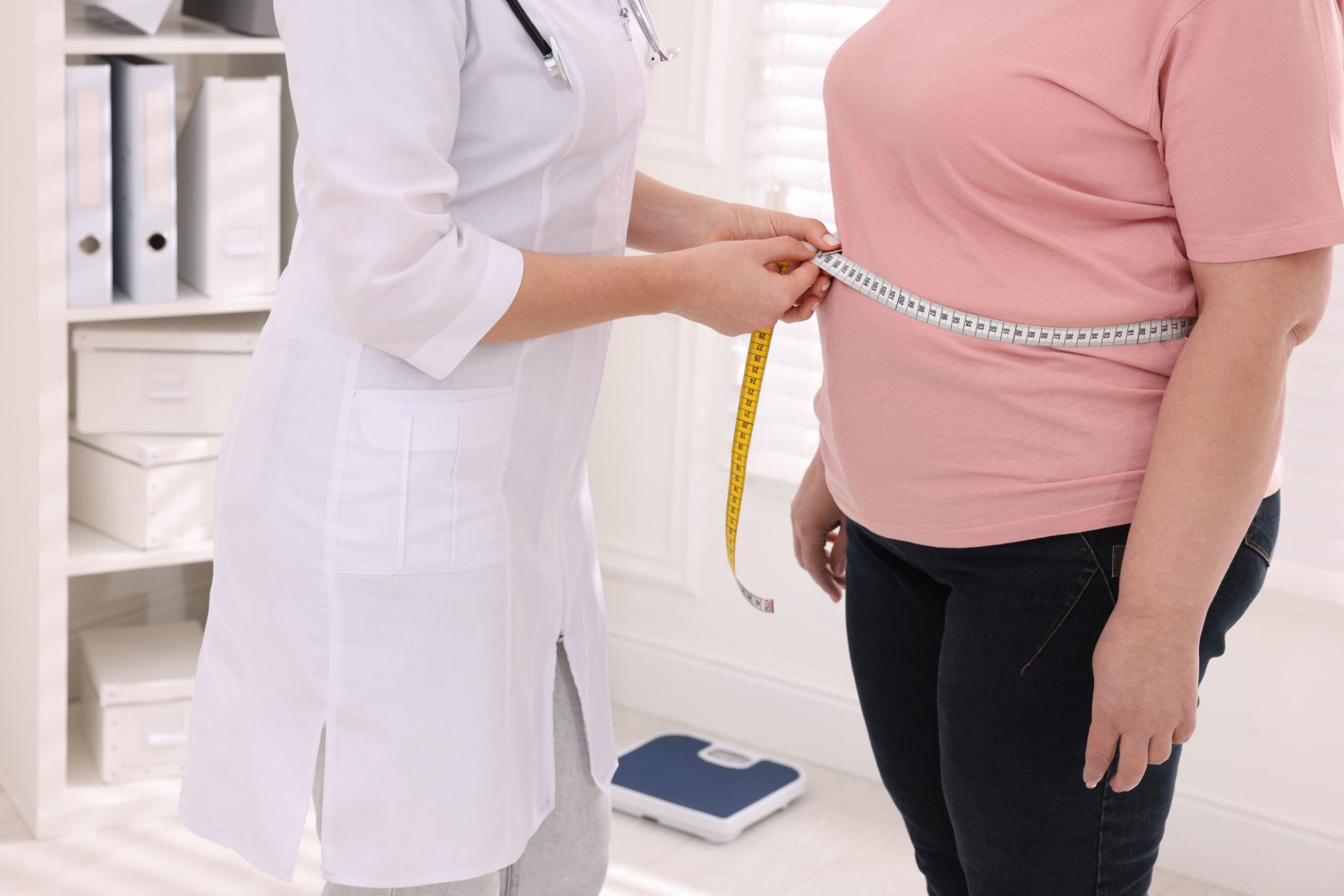 Nutricionista mide la cintura de una mujer con sobrepeso con cinta adhesiva en la clínica, primer plano Nutricionista mide la cintura de una mujer con sobrepeso con cinta adhesiva en la clínica, primer plano