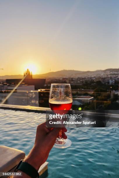 drinking wine by the rooftop swimming pool at sunset, personal perspective view - barcelona hotel stockfoto's en -beelden