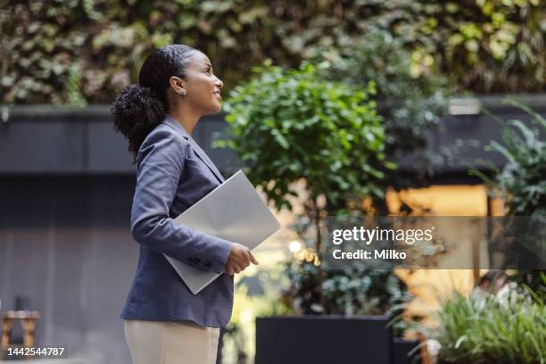 young business woman holding laptop and looking up - global mindset stock pictures, royalty-free photos & images