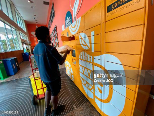 Delivery person loading packages into Amazon pick up locker outside Whole Foods in Palm Beach, Florida.