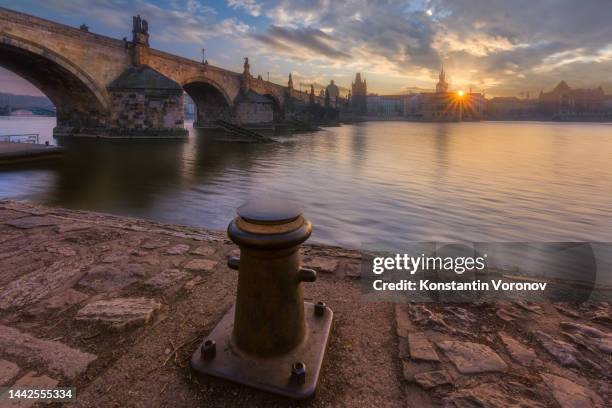 sunrise over prague. mooring bollard in the foreground. in the background is the charles bridge over the vllatva river. - rivière vltava photos et images de collection