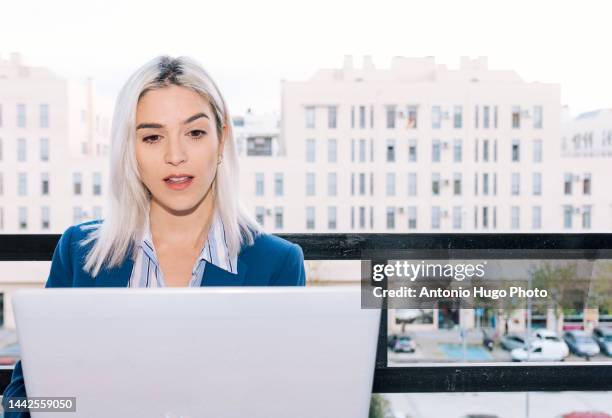 portrait of a young businesswoman with platinum hair working with her laptop from her terrace. business and technology concept. - metallic blazer stock pictures, royalty-free photos & images