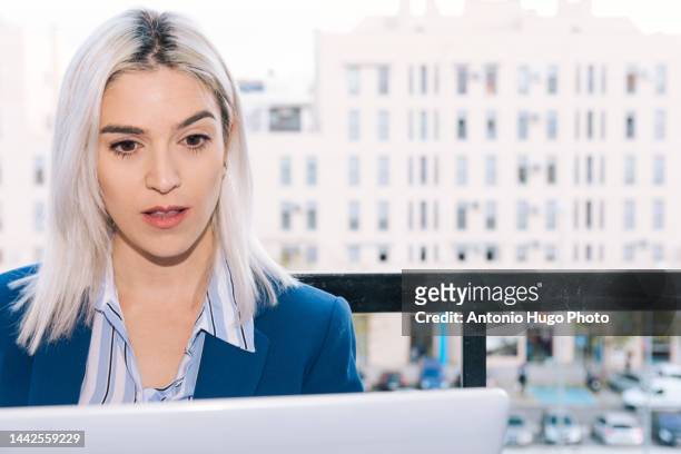 portrait of a young businesswoman with platinum hair working with her laptop from her terrace. business and technology concept. - metallic blazer stock pictures, royalty-free photos & images
